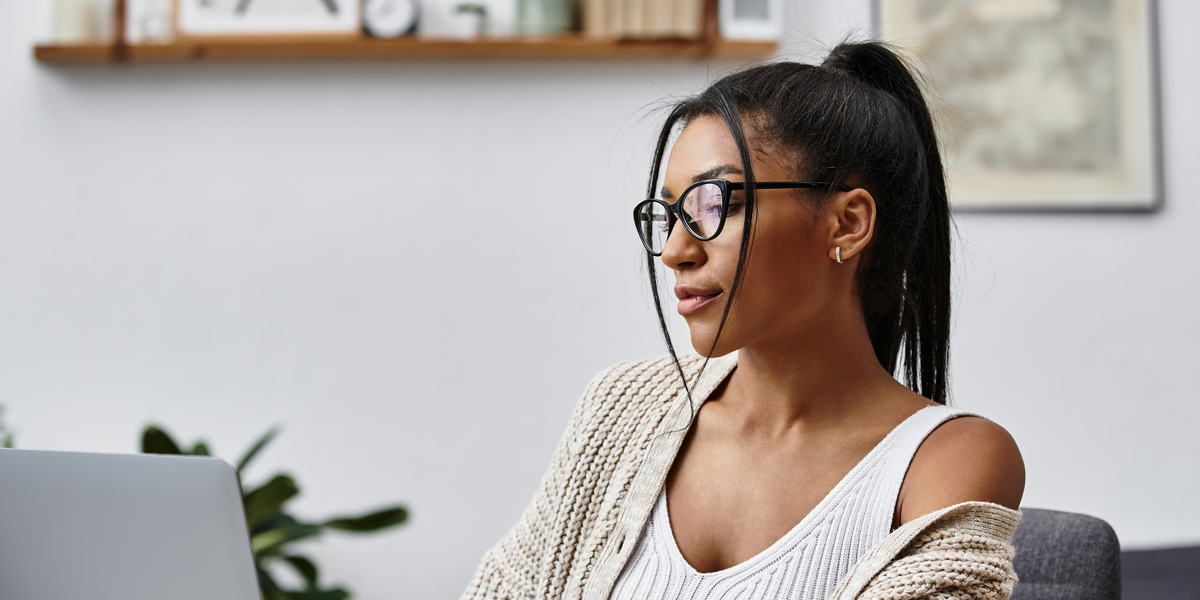 A beautiful young woman is engaged in remote learning, tapping away on her laptop at home.