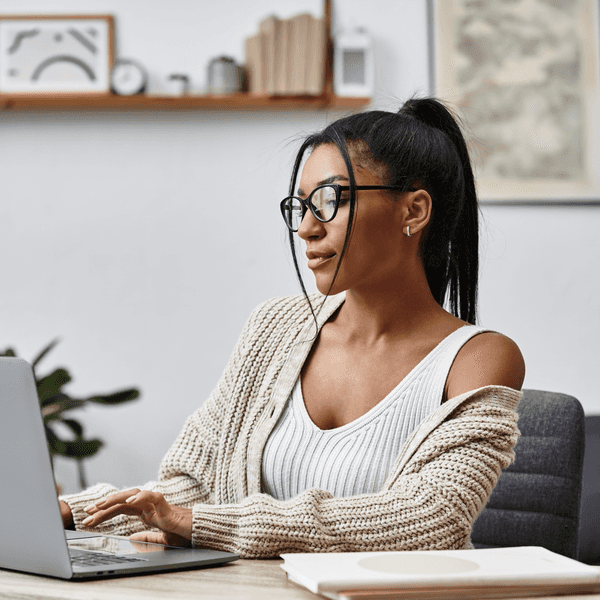 A beautiful young woman is engaged in remote learning, tapping away on her laptop at home.