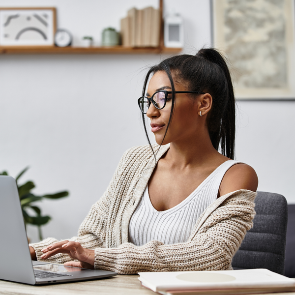 A beautiful young woman is engaged in remote learning, tapping away on her laptop at home.