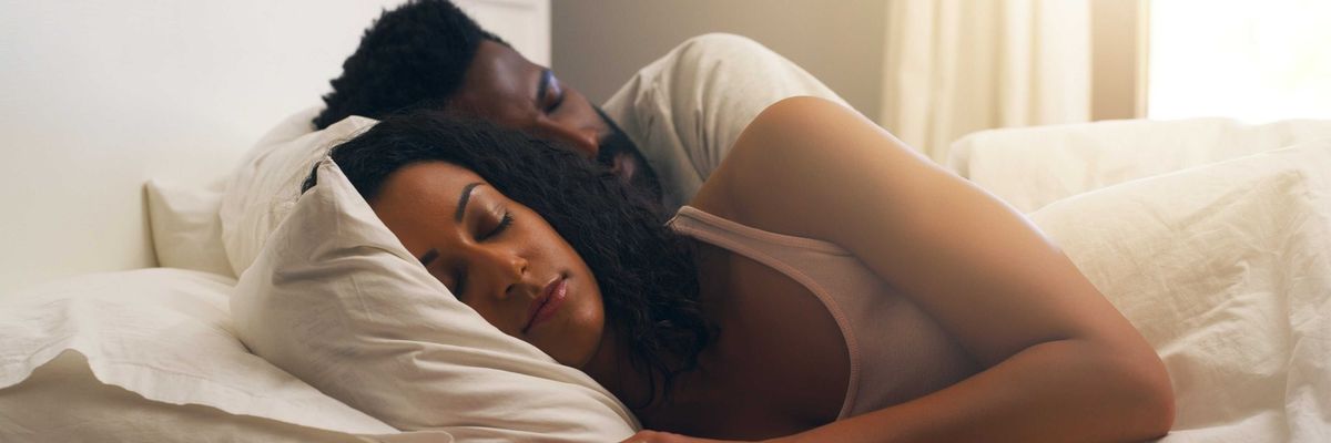 A Black couple peacefully asleep in soft light with a serene expression, deep rest while dreaming.