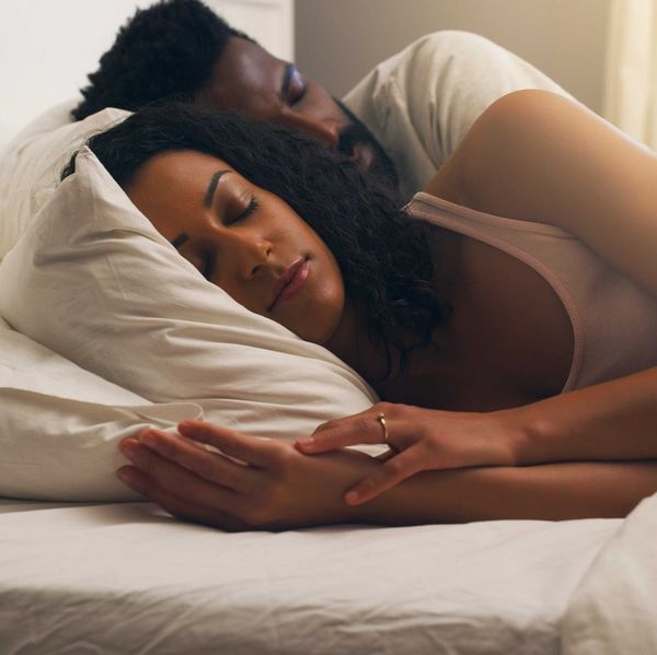 A Black couple peacefully asleep in soft light with a serene expression, deep rest while dreaming.