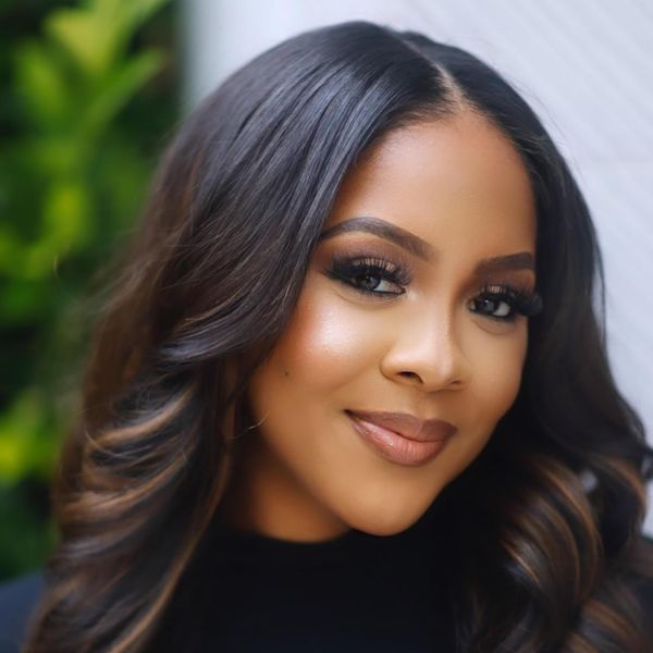 A Black woman looks into the camera and gives a closed-mouth smile. She's wearing a black turtleneck