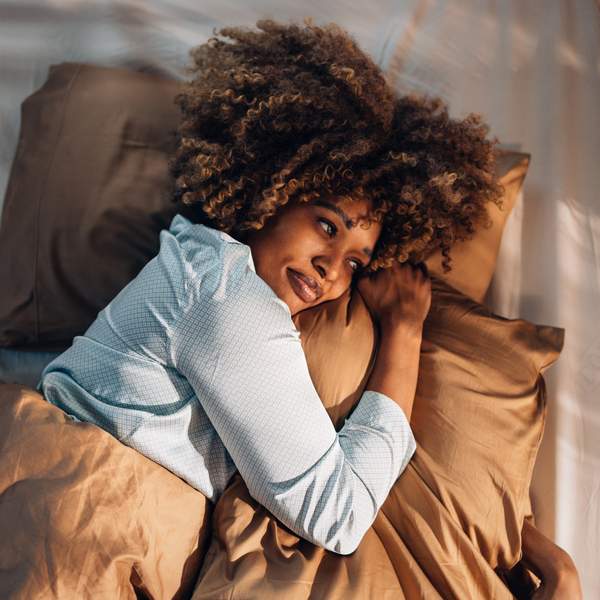 A From Above View Of A Happy Beautiful Woman In Pajamas Looking Away While Lying In Bed