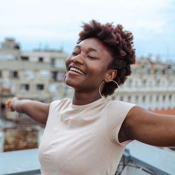 A-young-African-American-woman-standing-on-the-rooftop-with-her-arms-open-and-eyes-closed