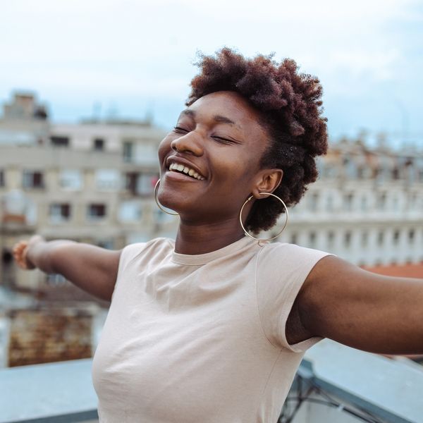 A-young-African-American-woman-standing-on-the-rooftop-with-her-arms-open-and-eyes-closed