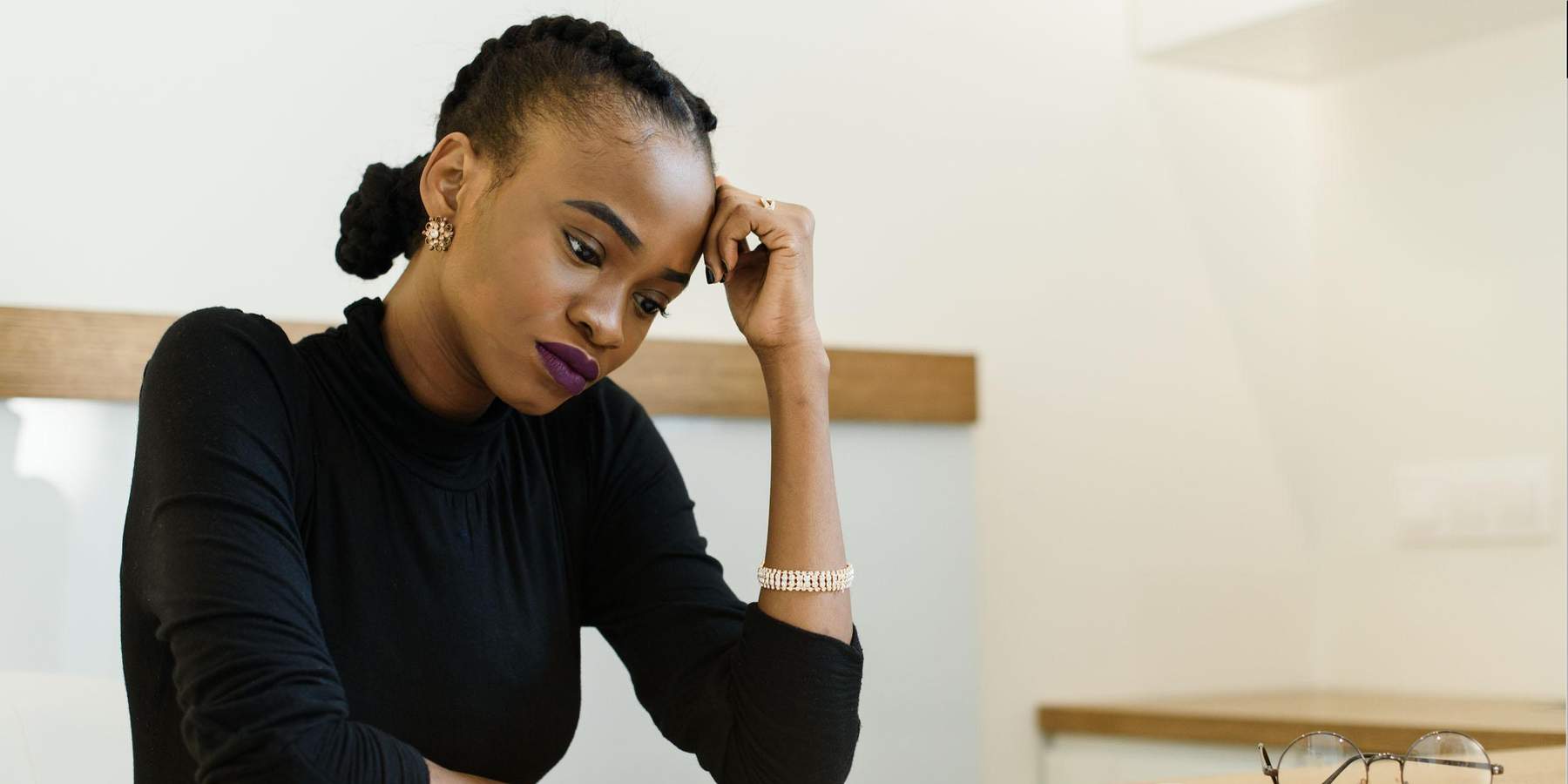 African-American woman in black shirt sitting at wooden desk in fustration