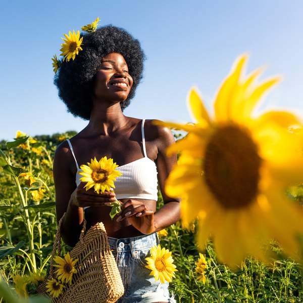 Beautiful african woman with curly afro style hair in a sunflowers field