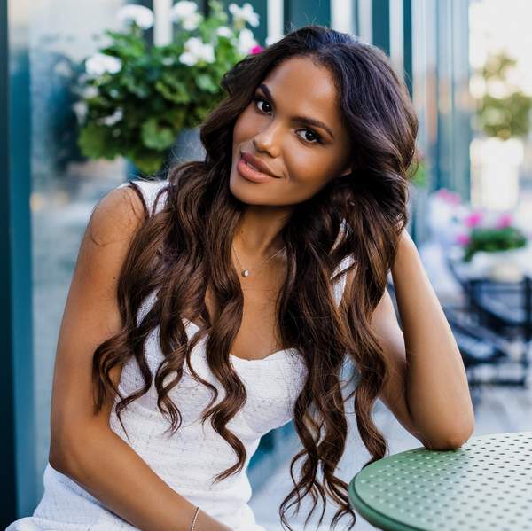 Beautiful portrait of an American girl with long curly hair sitting on a flyer in a cafe. woman smiling outdoors