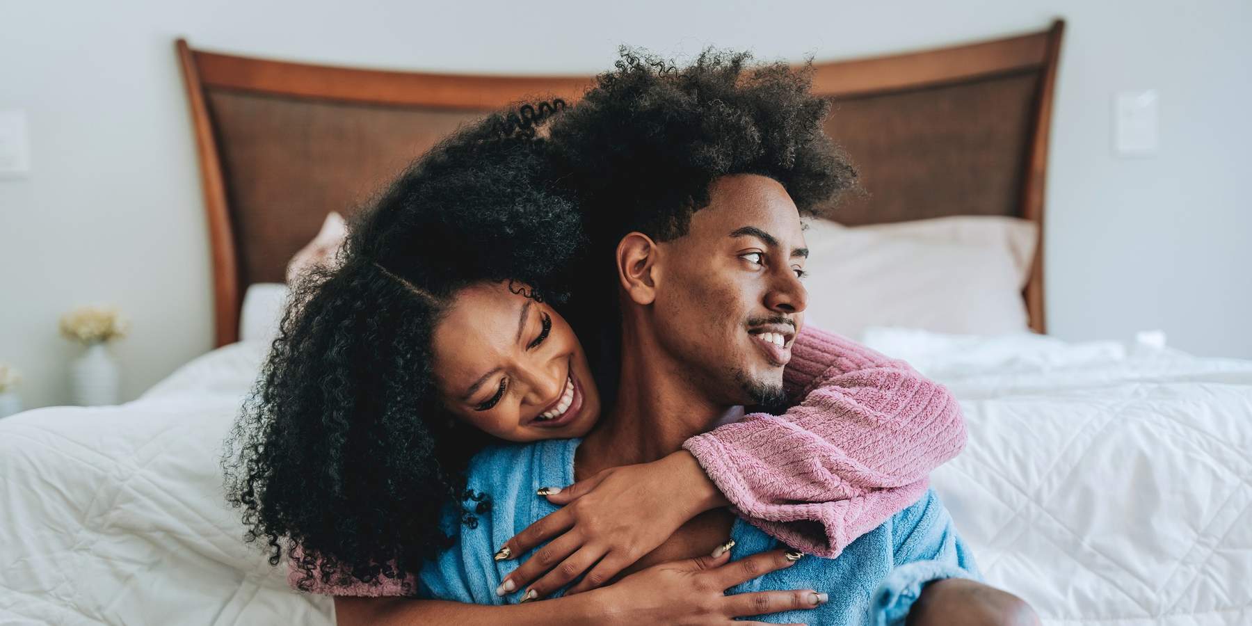 Black-couple-in-a-loving-embrace-wearing-bath-robes-by-a-bed