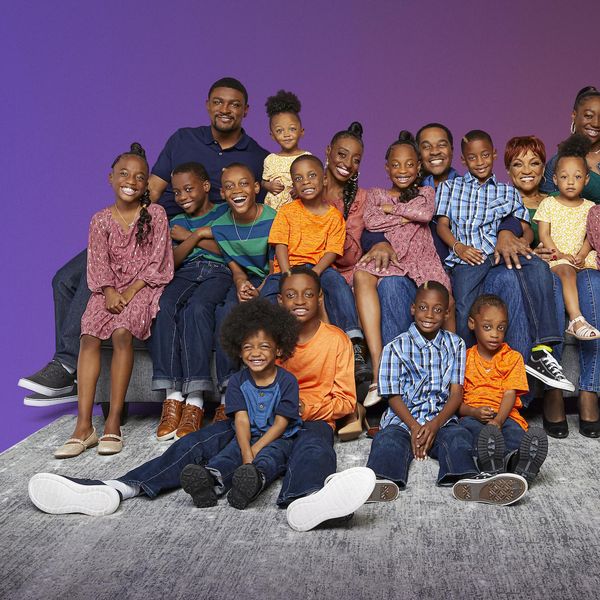 Black mother and father and their 14 children, sets of twins and triplets wearing bright colors