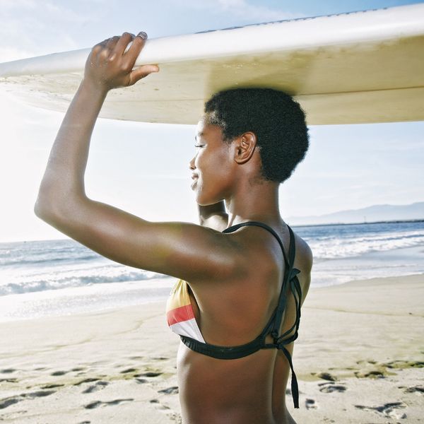 Black-woman-balancing-surfboad-on-her-head-at-the-beach