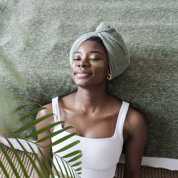Black-woman-doing-skincare-treatment-at-home-leaning-against-bed
