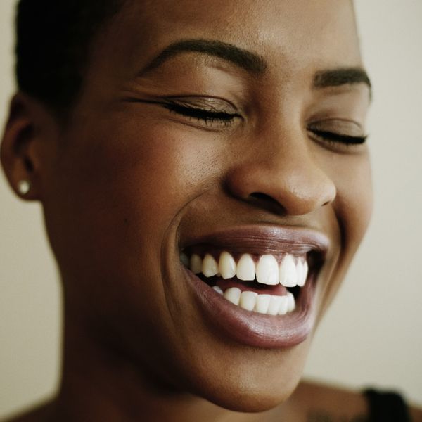 Black-woman-grinning-with-her-eyes-closed-showing-brilliant-white-smile