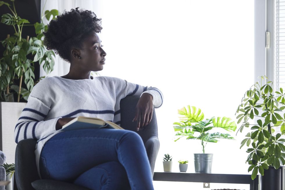 Black-woman-in-a-daze-gazing-out-her-window-while-reading