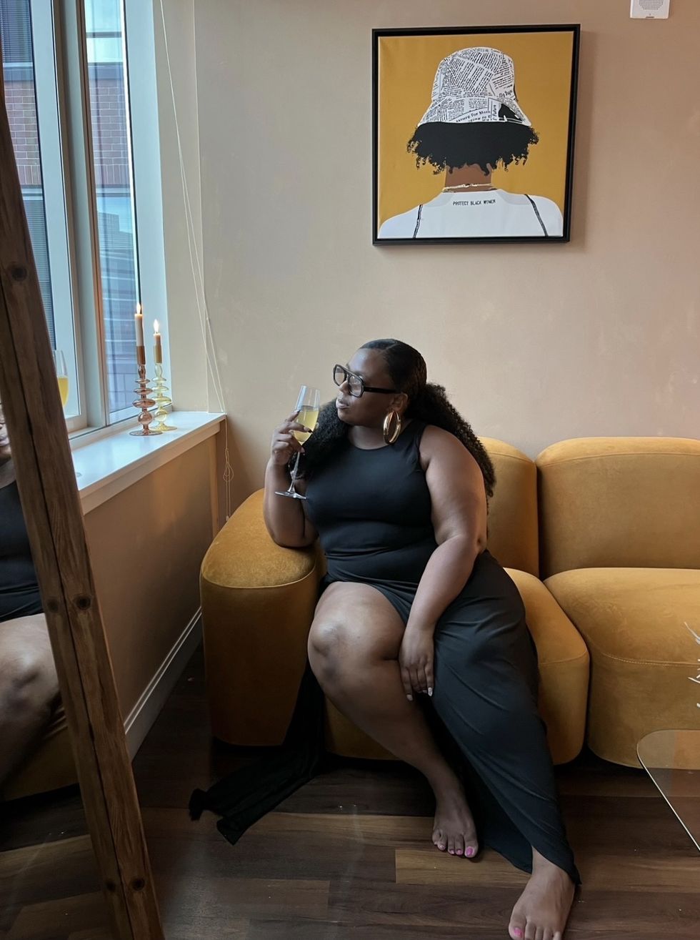 Black-woman-luxury-living-posing-on-her-couch-with-glass-of-champagne-in-hand