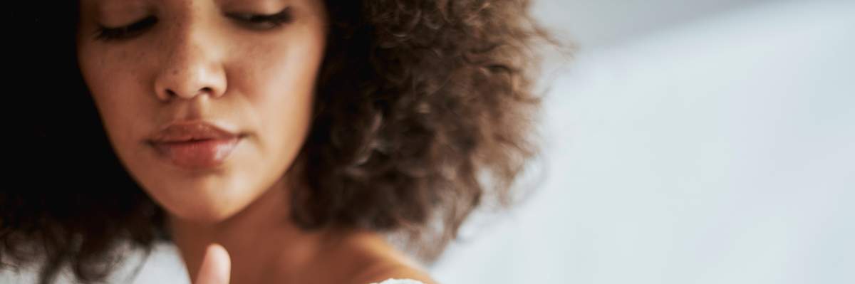 Black-woman-rubbing-moisturizer-cream-into-her-skin