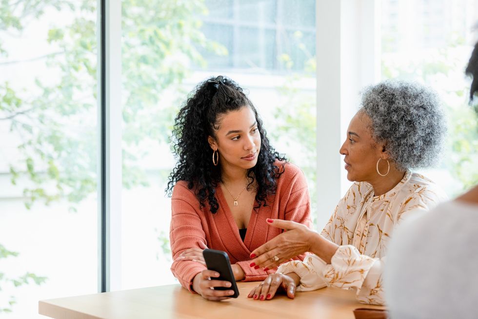 Black woman showing something on her phone to her mom.