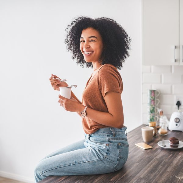 black-woman-smiling-eating-yogurt-sitting-on-kitchen-table