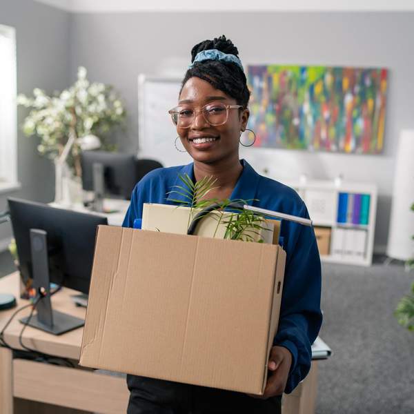 Black woman smiling with box of things from her office space