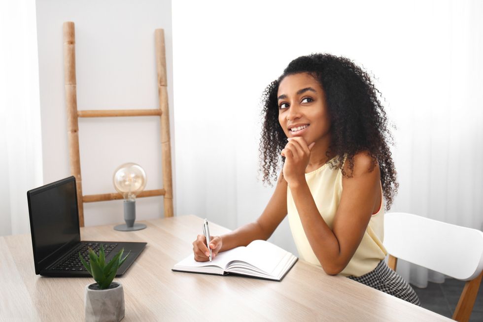 Black woman thinking writing in notebook