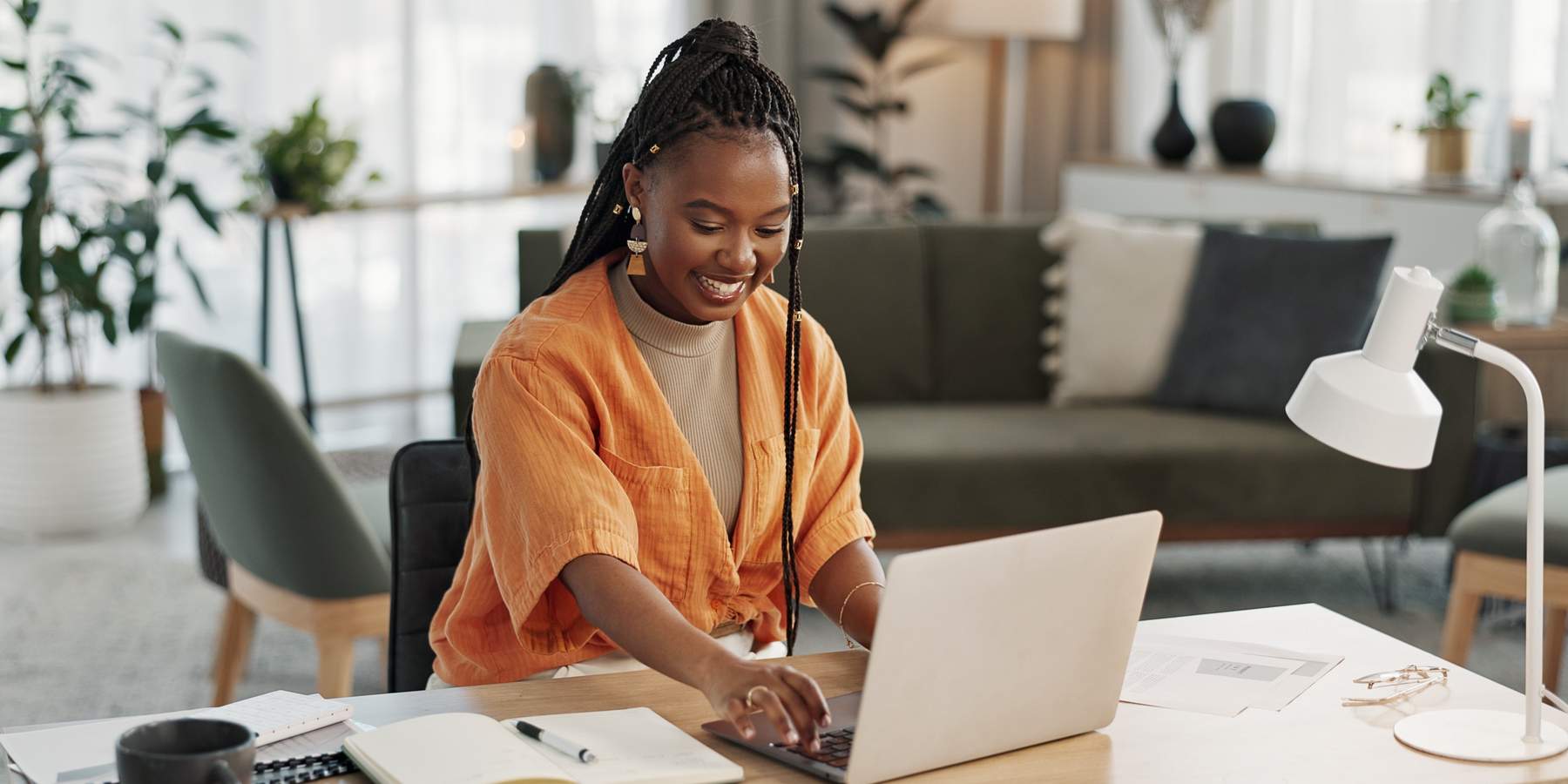 Black woman, typing in home office and laptop for research in remote work, social media or blog in apartment. Freelance girl at desk with computer writing email, website post and online chat in house