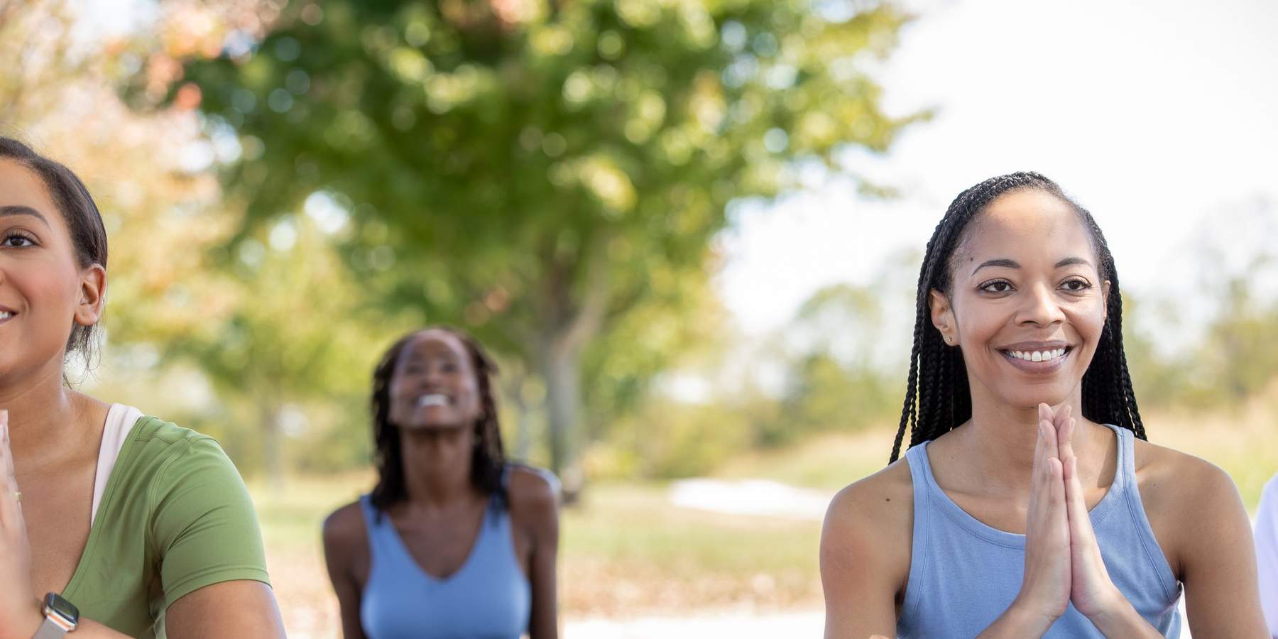 Black-women-posing-with-hand-over-heart-during-an-outdoor-yoga-class