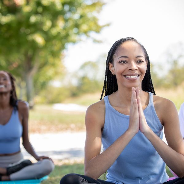 Black-women-posing-with-hand-over-heart-during-an-outdoor-yoga-class