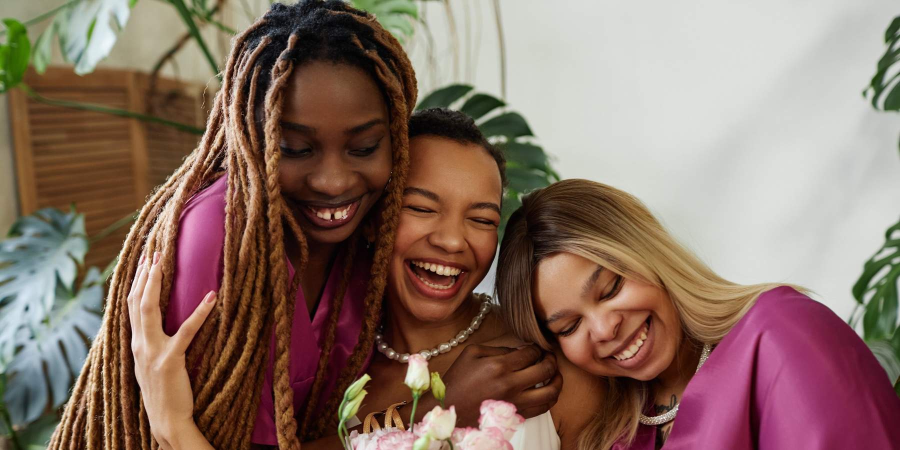 Candid waist up portrait of happy black woman as young bride embracing bridesmaids during wedding ceremony