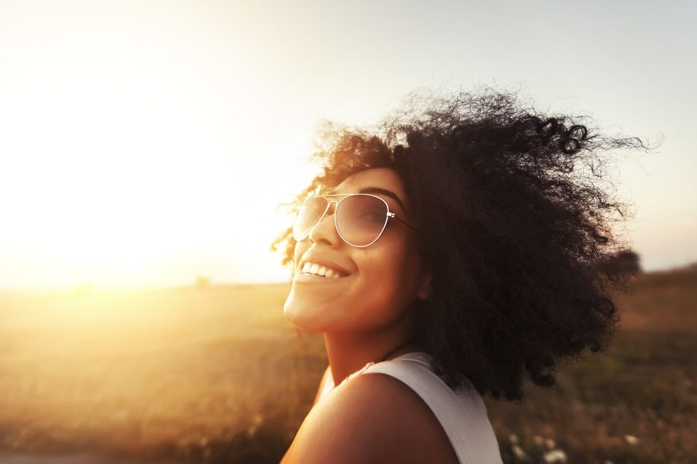 Cheerful-Black-woman-bathing-in-sunlight-smiling-at-the-sky