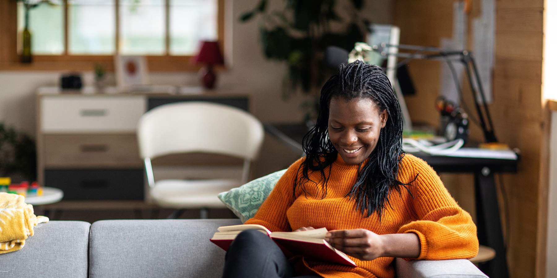 Cheerful-woman-turning-pages-of-her-book-reading-on-the-couch