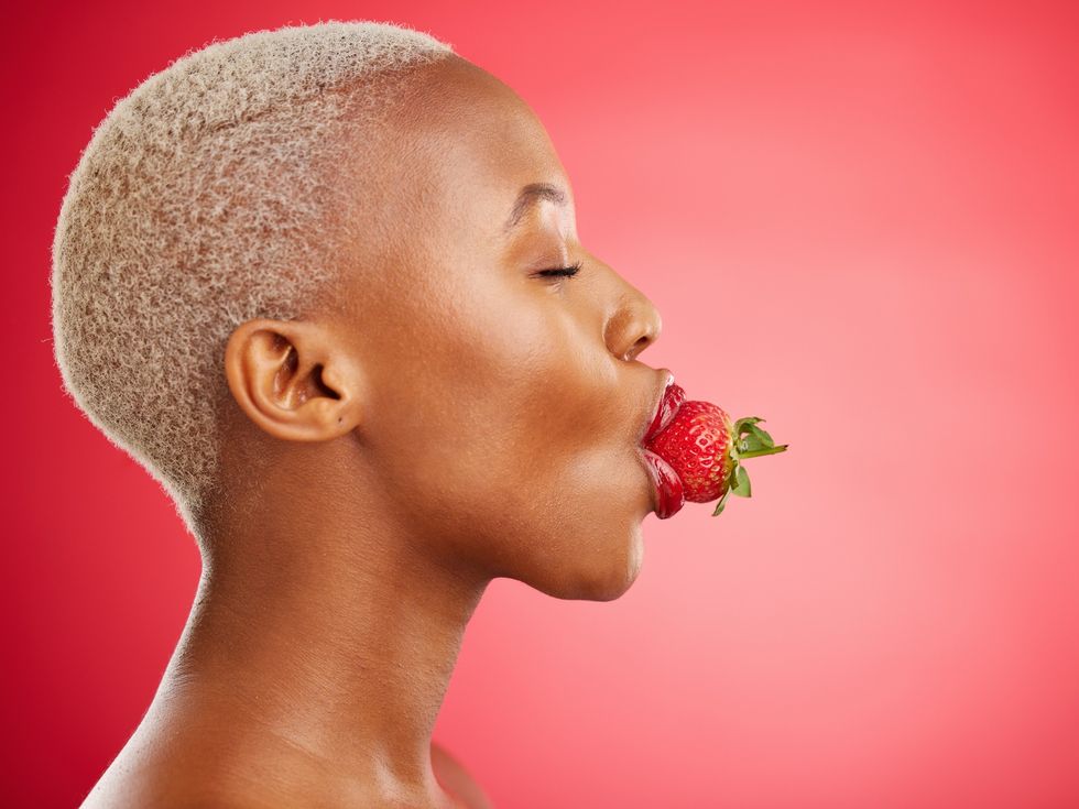 Close-up-of-Black-woman-side-profile-with-a-strawberry-in-her-mouth