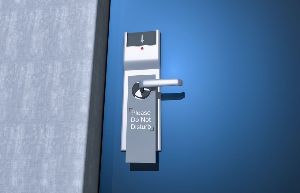 Close-up-of-hotel-room-door-with-do-not-disturb-sign-on-doorknob