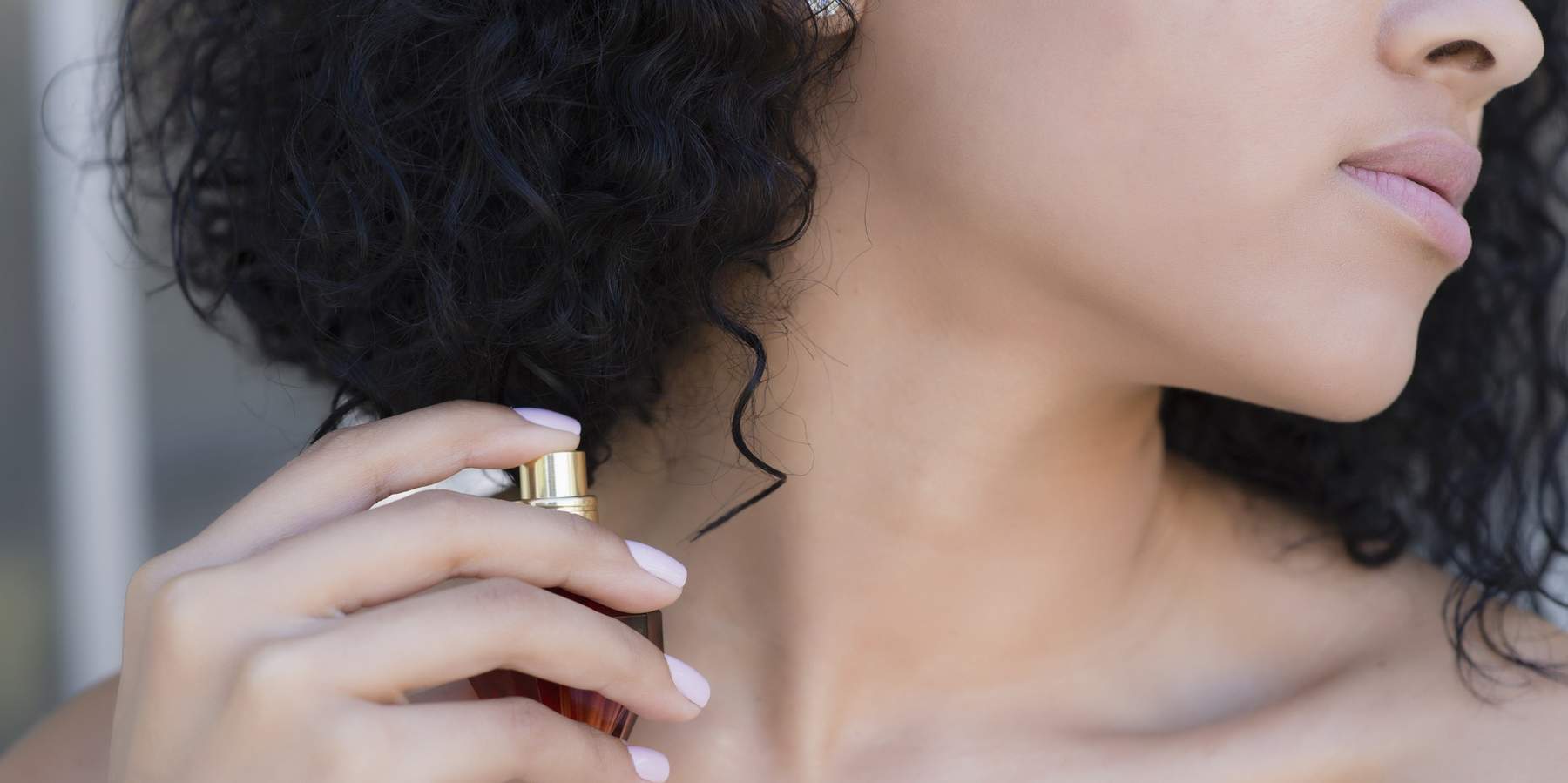 Close-up-of-naked-woman-spraying-fragrance-onto-her-neck
