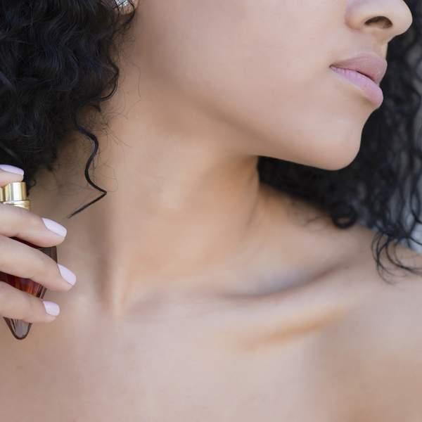 Close-up-of-naked-woman-spraying-fragrance-onto-her-neck