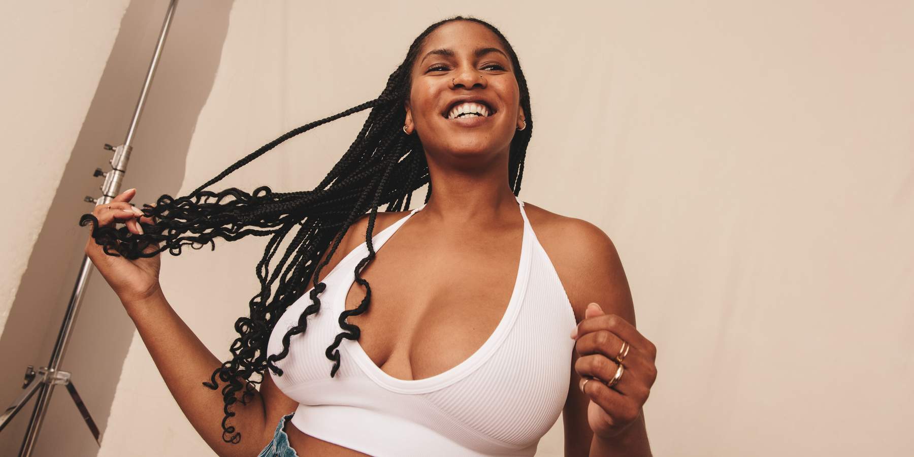 Comfortable in a bra. Happy young woman looking away with a smile on her face while standing against a studio background. Confident young woman embracing her natural body.
