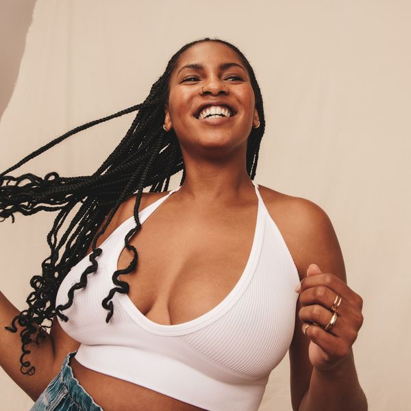 Comfortable in a bra. Happy young woman looking away with a smile on her face while standing against a studio background. Confident young woman embracing her natural body.