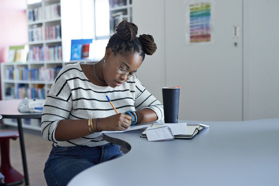 confident-young-woman-wearing-glasses-writing-notes-in-university