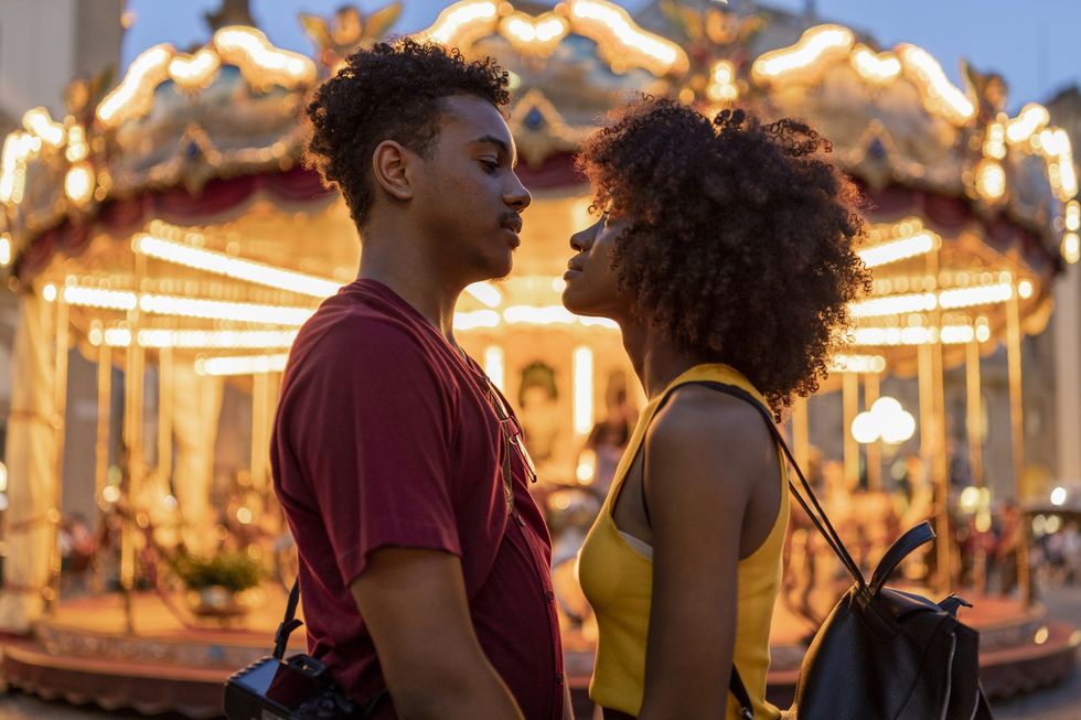 couple-locked-in-a-stare-while-standing-in-front-of-a-carousel