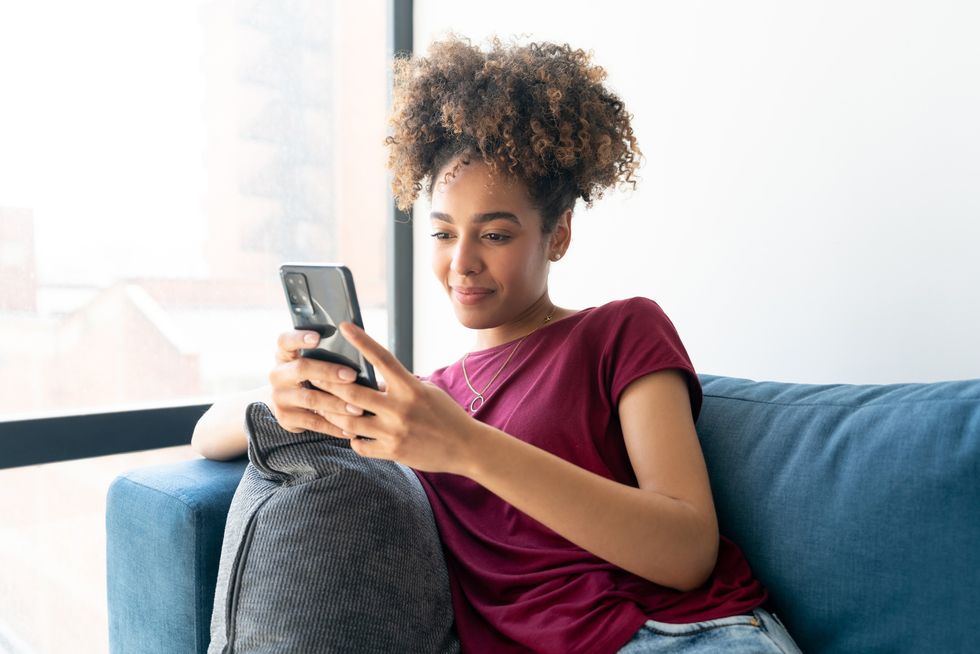 Happy-Black-woman-relaxing-at-home-and-texting-on-her-cell-phone-lifestyle