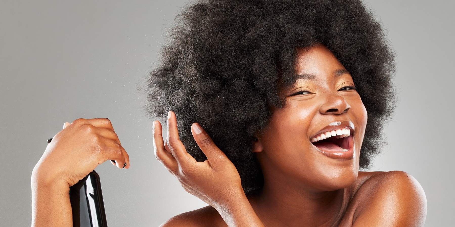 Happy-Black-woman-spraying-her-afro-with-bond-building-treatment