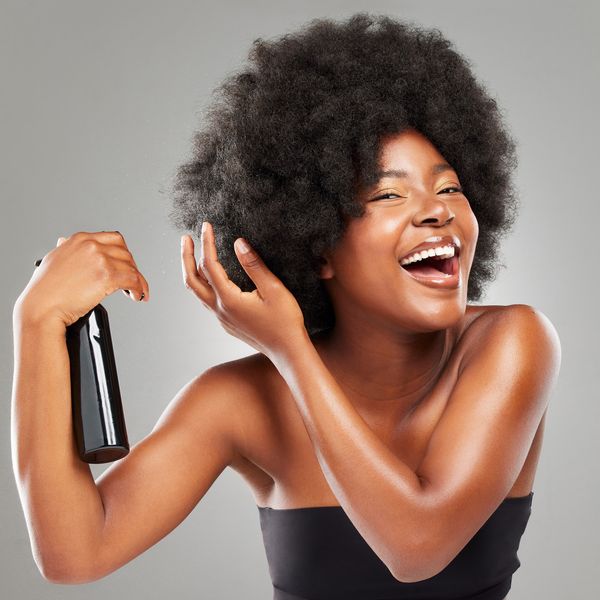 Happy-Black-woman-spraying-her-afro-with-bond-building-treatment