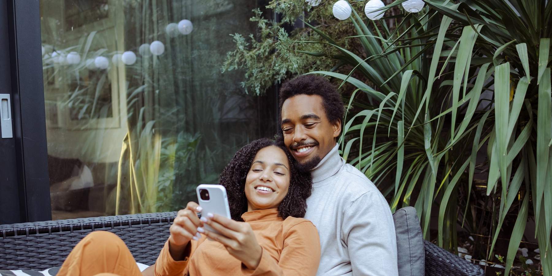 Happy-young-African-American-couple-enjoying-leisure-time-together-while-scrolling-phone-dating-apps