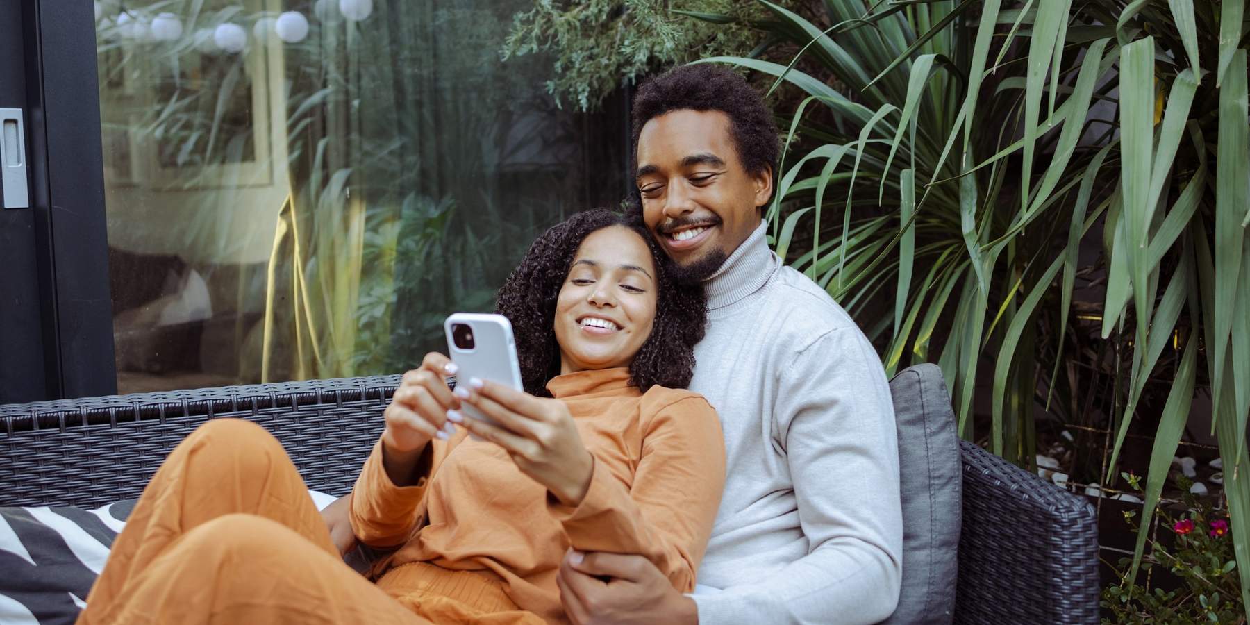 Happy-young-African-American-couple-enjoying-leisure-time-together-while-scrolling-phone-dating-apps