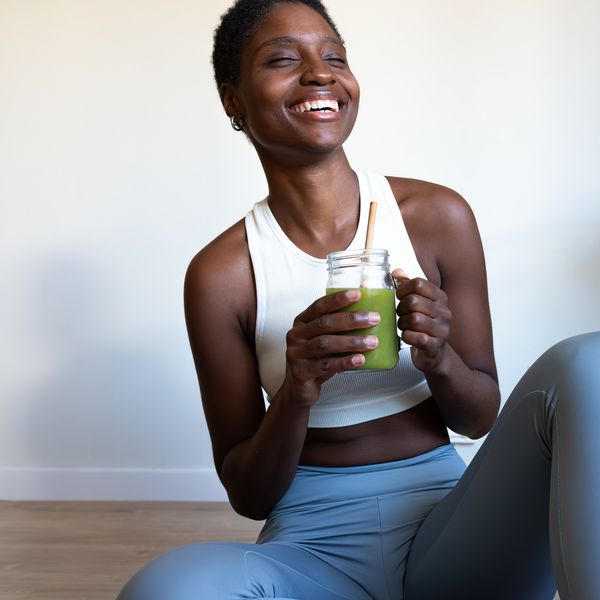 Happy-young-Black-woman-in-her-yoga-pants-drinking-green-juice-wellness-aesthetic