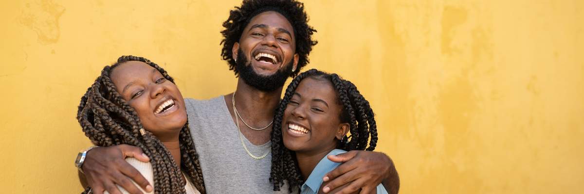 hugging-friendship-group-laughing-against-yellow-wall