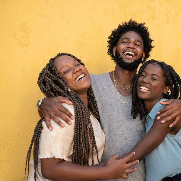 hugging-friendship-group-laughing-against-yellow-wall