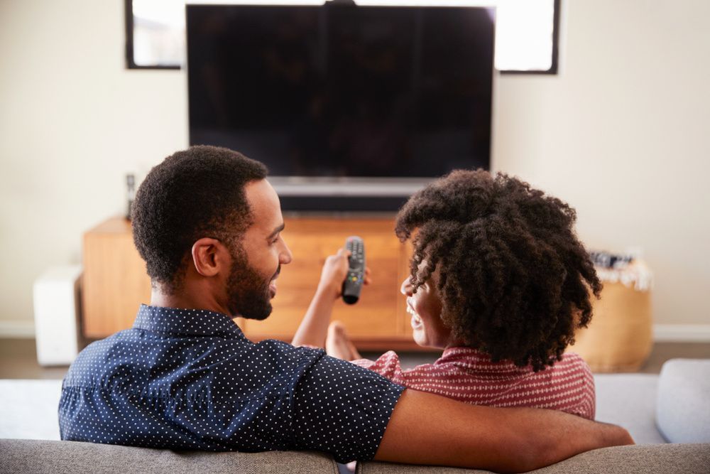 black-couple-remote-sitting-on-couch-tv