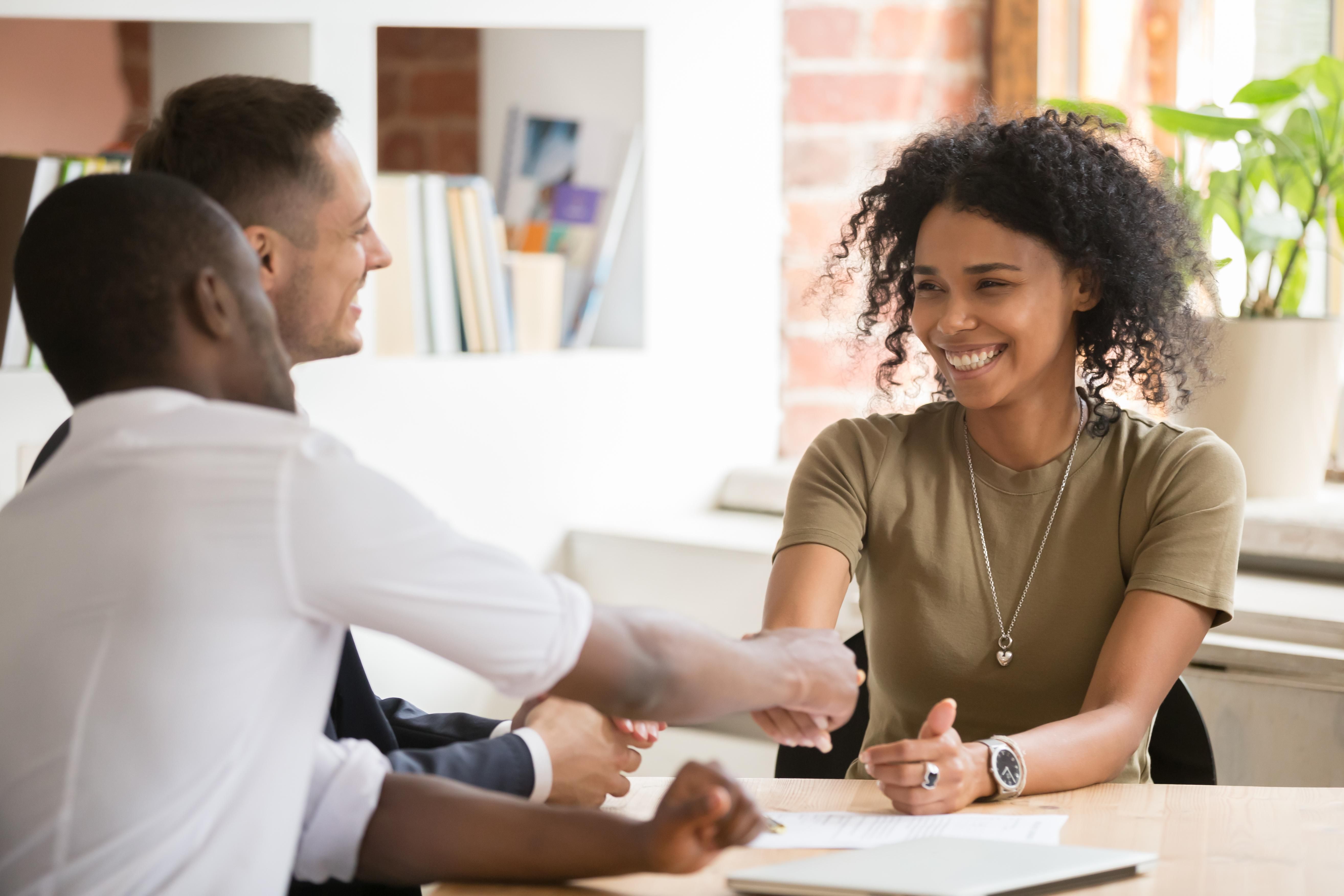 black woman with natural curly hair shakes hands with black man as man smiles in an interview