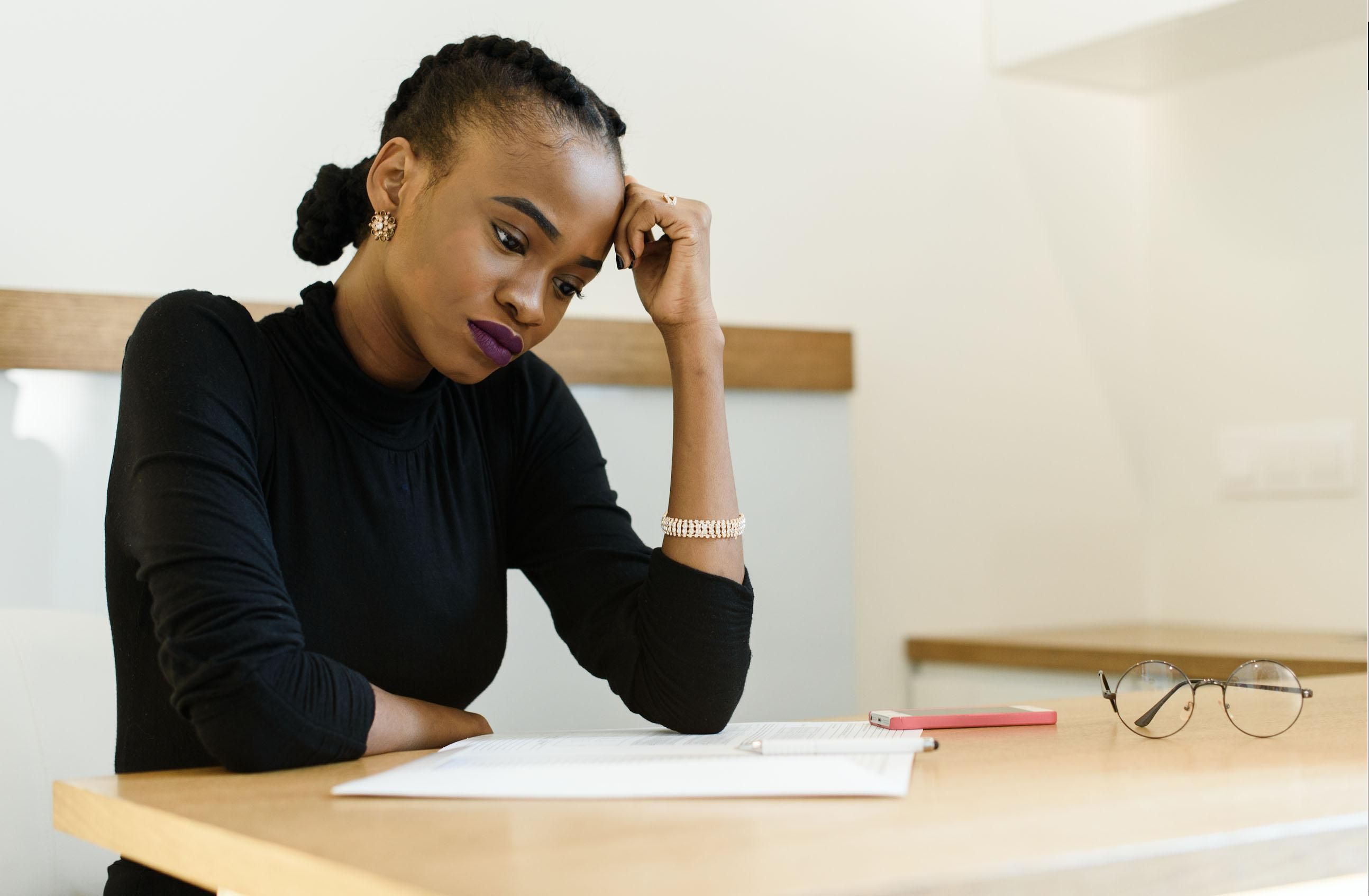 African-American woman in black shirt sitting at wooden desk in fustration