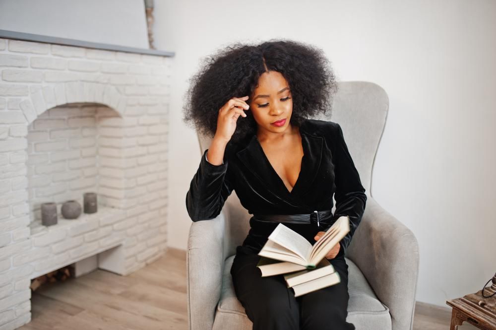 stylish-black-woman-reading-fireplace